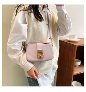 Detail view of lavender faux leather shoulder bag featuring a vintage gold circular buckle