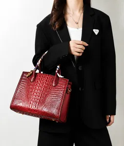 Detalle de bolso rojo con motivo de cocodrilo y elegante pañuelo de seda en el asa