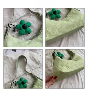 Detail view of light green checkered shoulder bag with flower charm and metal zipper