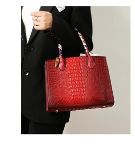 Detalle del bolso rojo con textura de cocodrilo y un pañuelo de seda decorativo en el asa