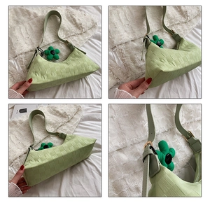 Detail view of a green woven hobo bag featuring a sunflower charm and textured finish