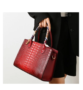 Detalle de bolso rojo con relieve de cocodrilo y pañuelo de seda en el asa superior