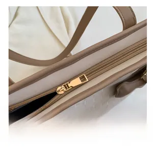 Detail shot of golden metal zipper and woven texture on this beige tote bag