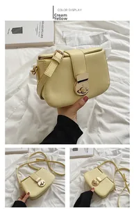 Detail view of cream yellow crossbody bag featuring a golden circular twist-lock buckle
