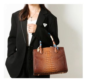 Detalle del bolso tote marrón oscuro con relieve de cocodrilo y pañuelo azul decorativo