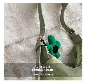 Detail of adjustable strap and gold buckle on a light green leather shoulder bag