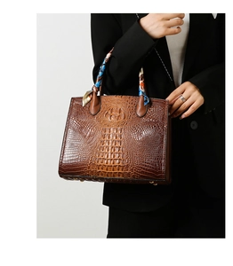 Detalle de la textura de cocodrilo y el asa con pañuelo de seda en el bolso marrón