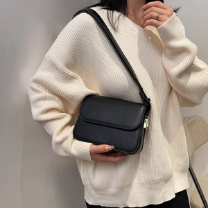 Detail of a black leather rectangular flap shoulder bag with gold metal hardware buckle