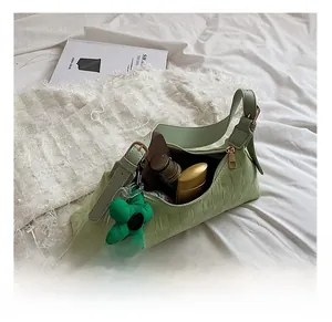 Detail view of green plaid shoulder bag interior capacity with cosmetic items