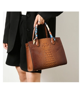 Detalle del bolso tote marrón oscuro con grabado de cocodrilo y pañuelo de seda floral