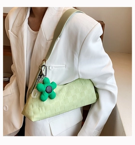 Detail of light green checkered underarm bag with green flower charm and textured fabric