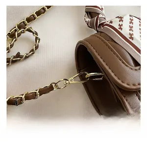 Detail of dark brown quilted leather bag with gold hardware and silk scarf accent