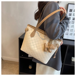 Detail of cream woven tote bag with brown straps and cute leather dog charm accessory