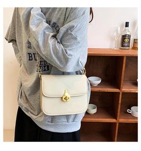 Close-up of beige vintage crossbody bag with elegant golden water-drop twist lock