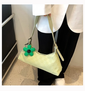 Detail of pistachio green checkerboard crescent bag worn on shoulder with flower charm