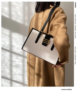 Detail of white crocodile embossed baguette bag with black straps and gold metal buckle