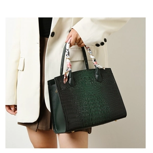 Detalle de bolso tote con patrón de cocodrilo y pañuelo de seda decorativo en asas