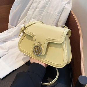 Pale yellow leather crossbody square bag with crown lock on a white shirt background