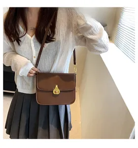 Classic dark brown leather crossbody bag with elegant gold twist lock hardware on model