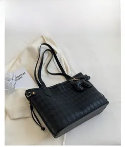 Detail of black large tote bag with quilted rhombus texture and dog charm accessory