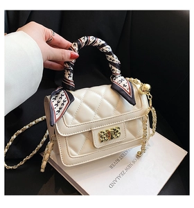 Close-up of beige quilted crossbody bag with silk scarf wrapped handle and gold chain
