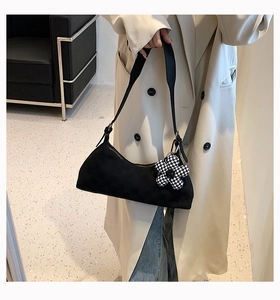 Detail of black underarm bag featuring a trendy checkerboard flower charm and zip closure