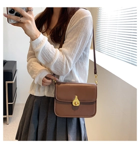 Detail of vintage brown shoulder bag showing golden teardrop lock and matte leather texture