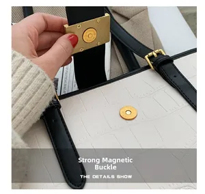 Close-up of golden strong magnetic buckle on white crocodile pattern handbag