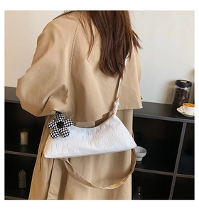 Detail of white embossed leather underarm bag with checkerboard flower pendant decoration