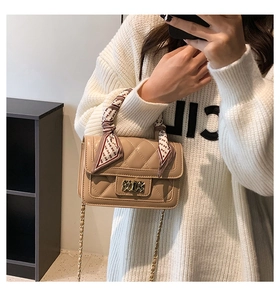 Beige quilted crossbody bag with silk scarf detail and gold metal buckle worn by model