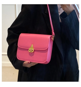 Pink leather crossbody bag with golden pear-shaped clasp styled on a black blazer