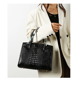 Detalle del bolso tote negro con grabado de cocodrilo y un pañuelo de seda decorativo