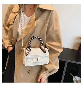 Close-up of a white quilted crossbody bag with a silk scarf wrapped handle and gold chain