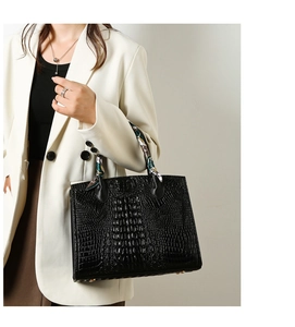 Detalle de bolso negro con textura de cocodrilo y pañuelo de seda decorativo