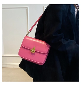 Detail of pink crossbody bag with gold vintage clasp on model's shoulder with black jacket