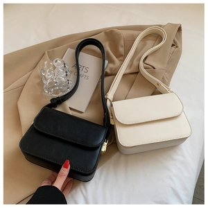 Close-up of minimalist black and cream crossbody bags with gold hardware details