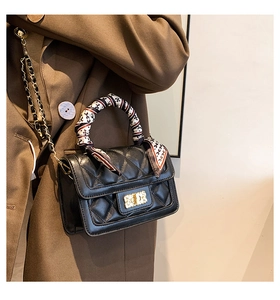 Close-up of black quilted leather crossbody bag with scarf-wrapped handle and gold lock
