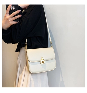Detail of cream white leather crossbody bag featuring an elegant gold pear-shaped twist lock