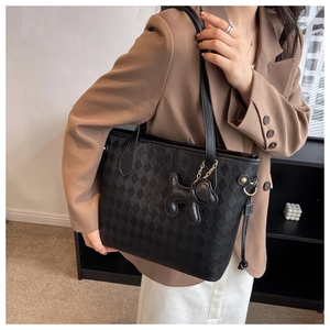 Close-up of black checkered PU tote bag with a cute puppy pendant for daily commute