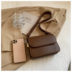 Detail of dark brown retro crossbody bag with gold hardware and adjustable strap