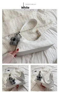 Detailed view of white faux leather shoulder bag with checkerboard flower charm