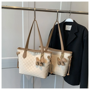 Detail of checkered PU tote bag with brown leather handles and a 3D dog charm decoration