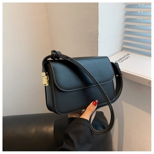 Detail of black faux leather square bag featuring a gold rectangular metal lock and strap