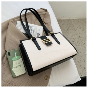 Detail of crocodile embossed leather texture with golden buckle on a white tote bag