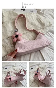 Close-up of pink checkered shoulder bag with plush flower charm and adjustable leather strap