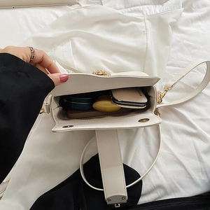 White leather crossbody bag with gold buckle showing spacious interior storage space