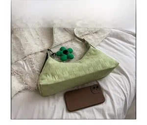 Detailed view of light green checkered shoulder bag with flower charm and phone for scale