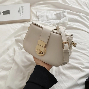 Minimalist beige crossbody bag featuring a round gold lock and adjustable strap