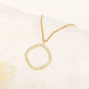 Dettaglio di una collana dorata geometrica con zirconi bianchi su una base di cristallo