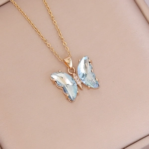 Elegant gold butterfly necklace with light blue gemstones on a soft pink velvet background